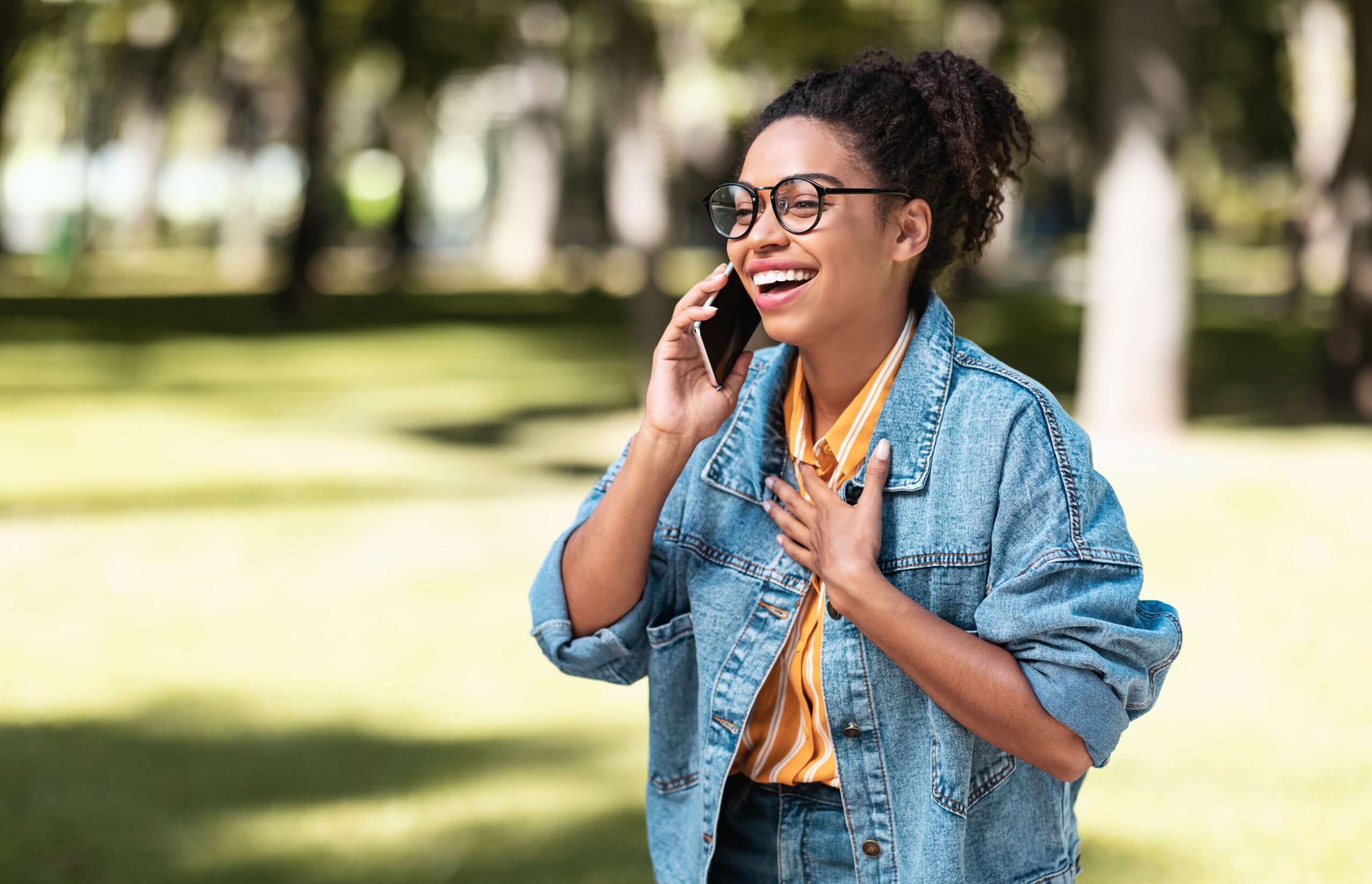 woman smiling and talking at the phone in a park