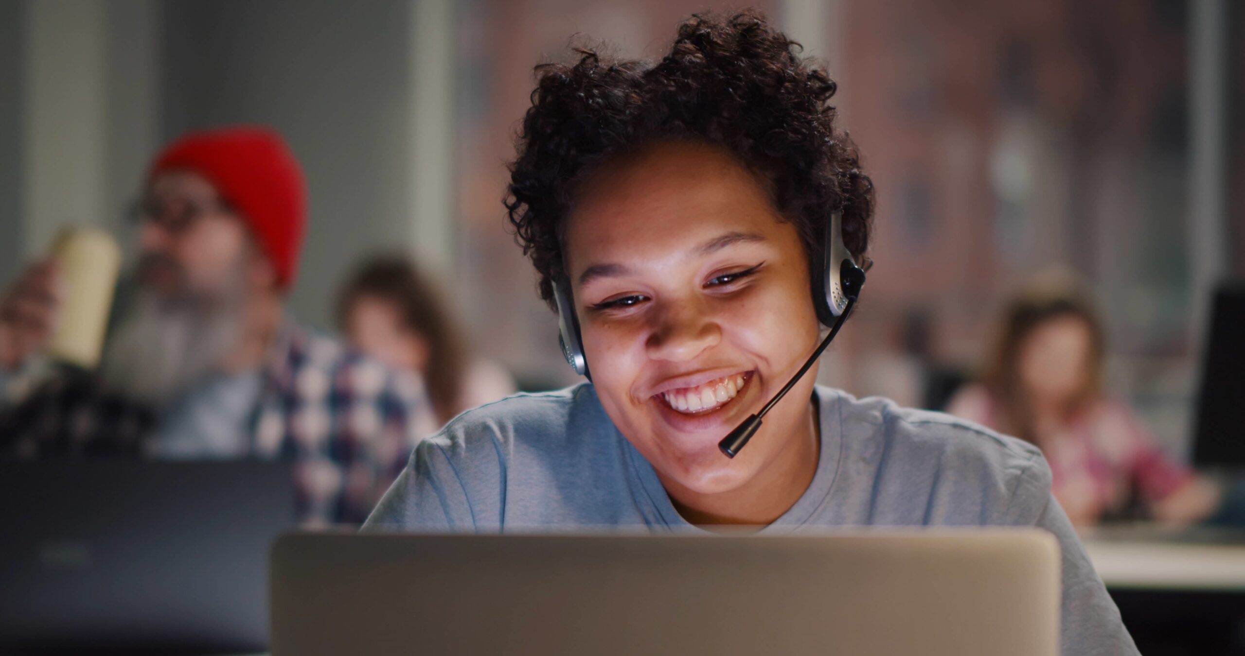 girl smiling while looking at her computer with heaphones and mic