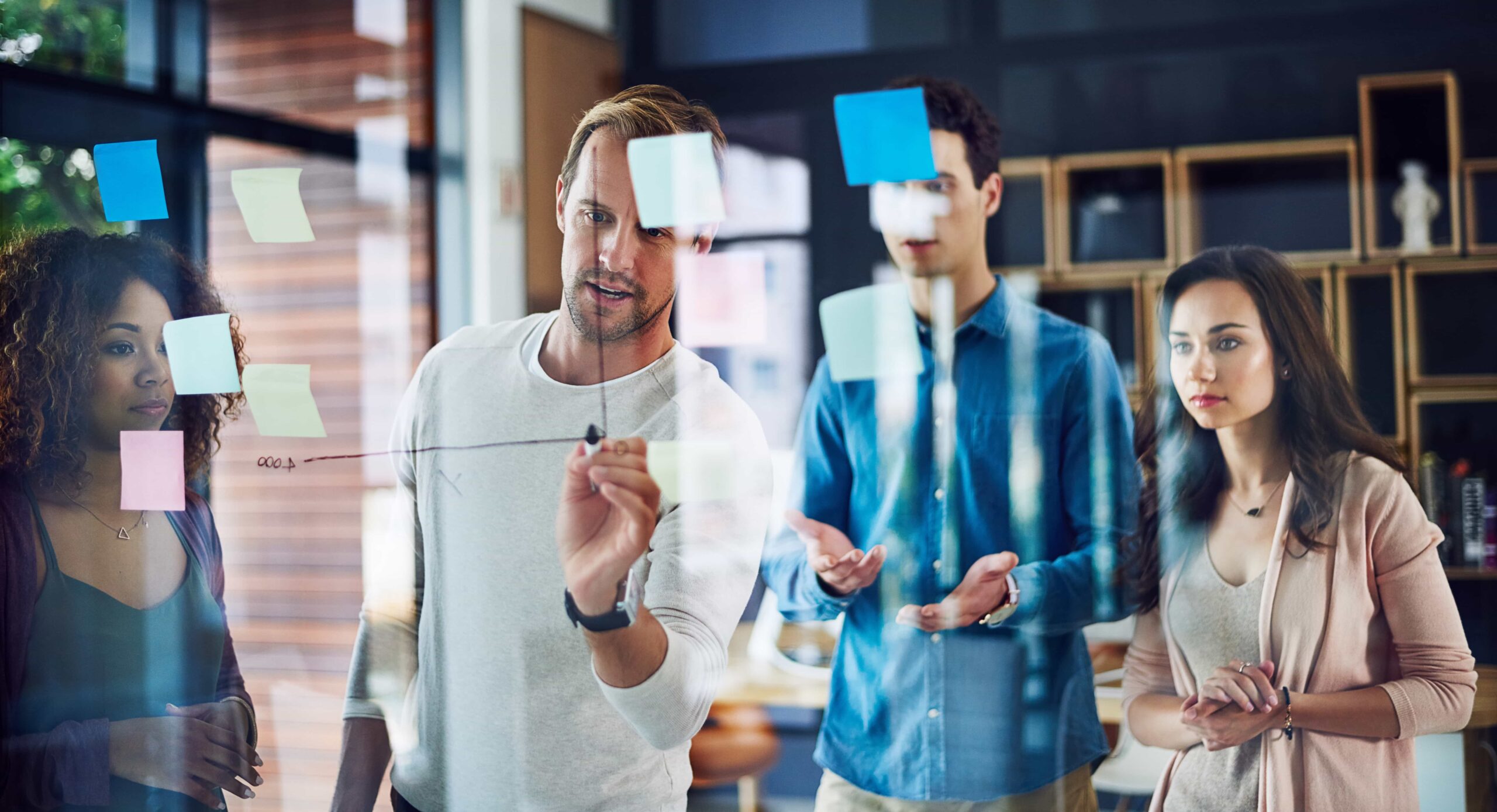 People in a work environment drawing a timeline on a glass board